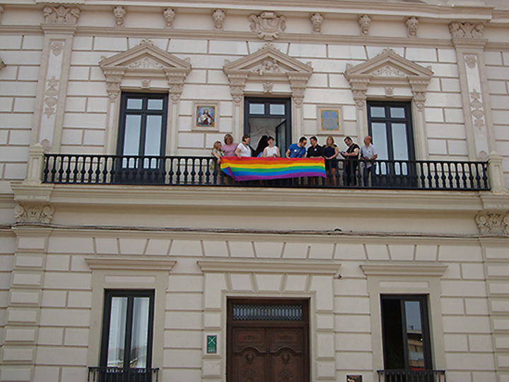 La alcaldesa, Rosa Melchor, junto a miembros del equipo de gobierno, han colgado la bandera en la fachada del ayuntamiento