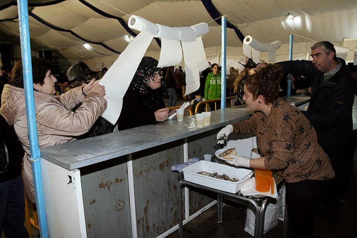 En pleno reparto de sardinas asadas, dentro de la Carpa